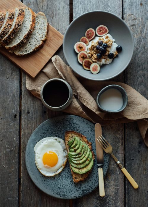 pexels-photo-5591663-5591663 Healthy breakfast with avocado toast, eggs, and yogurt with figs and berries on a wooden table.
